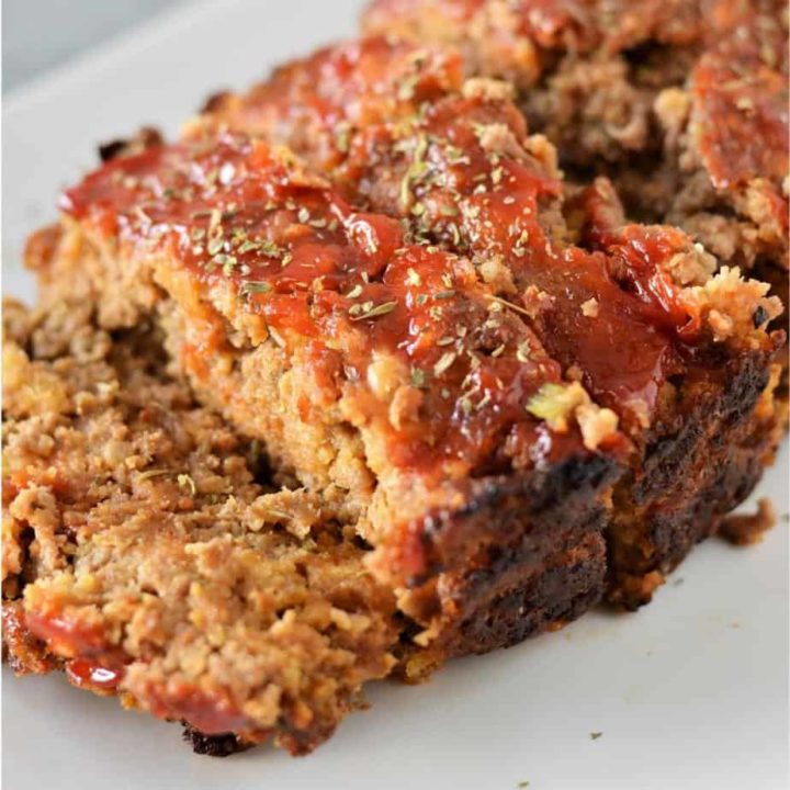 close up image of sliced stuffing meatloaf on white plate