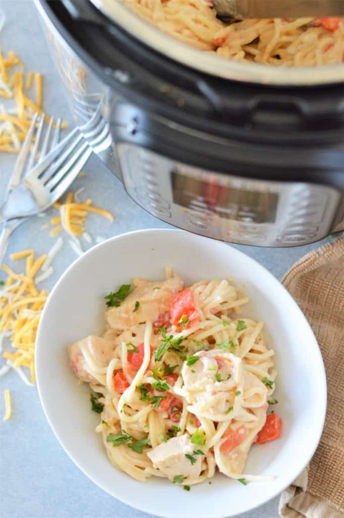 creamy chicken spaghetti in white bowl with instant pot in background