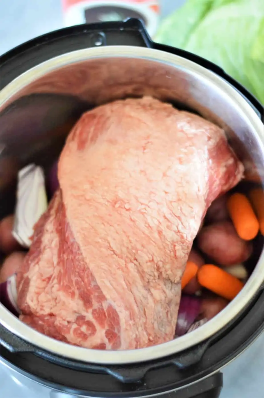 corned beef brisket sitting on top of carrots and potatoes in instant pot