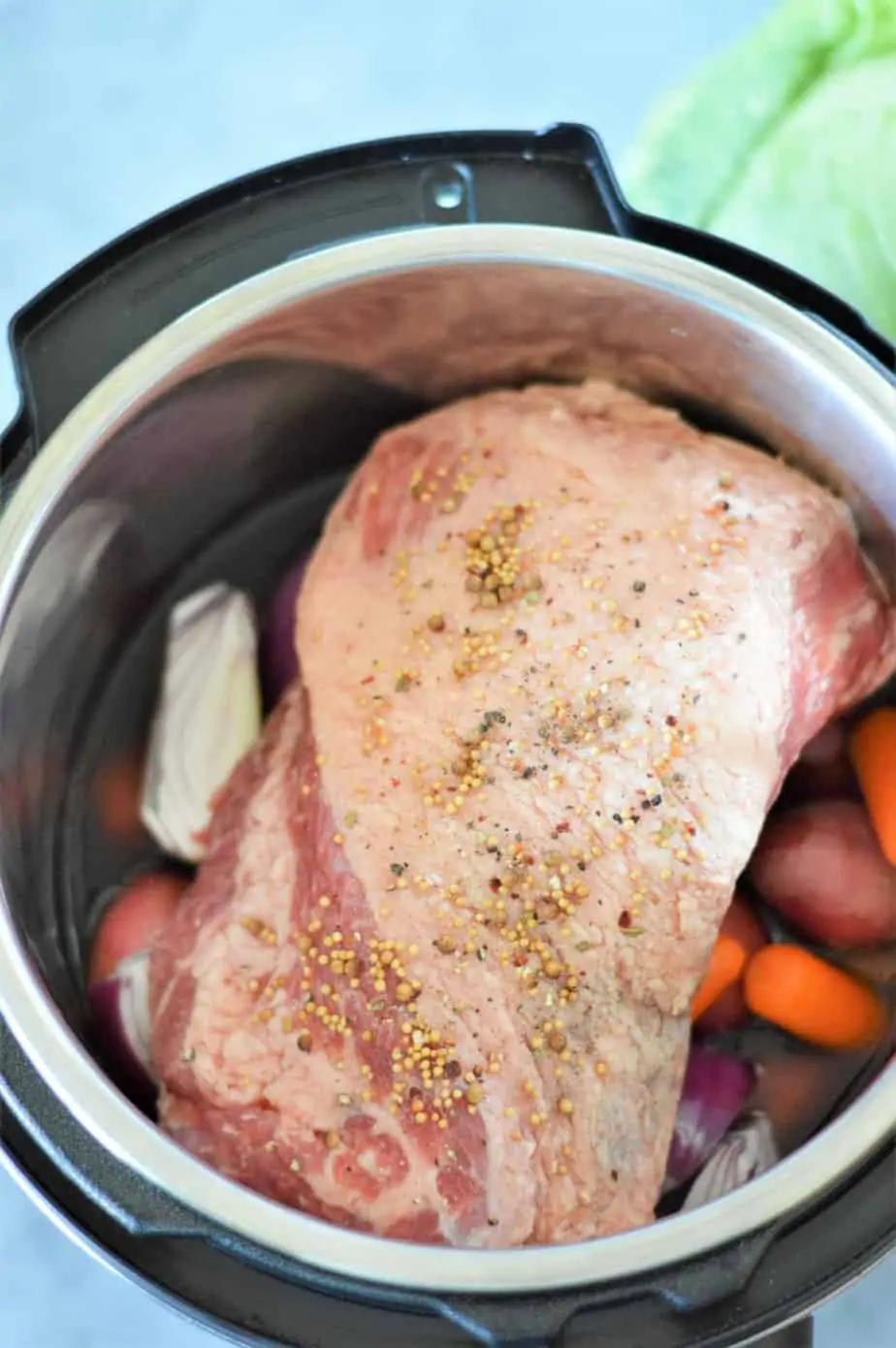 corned beef on top of carrots, onion and potatoes in an instant pot