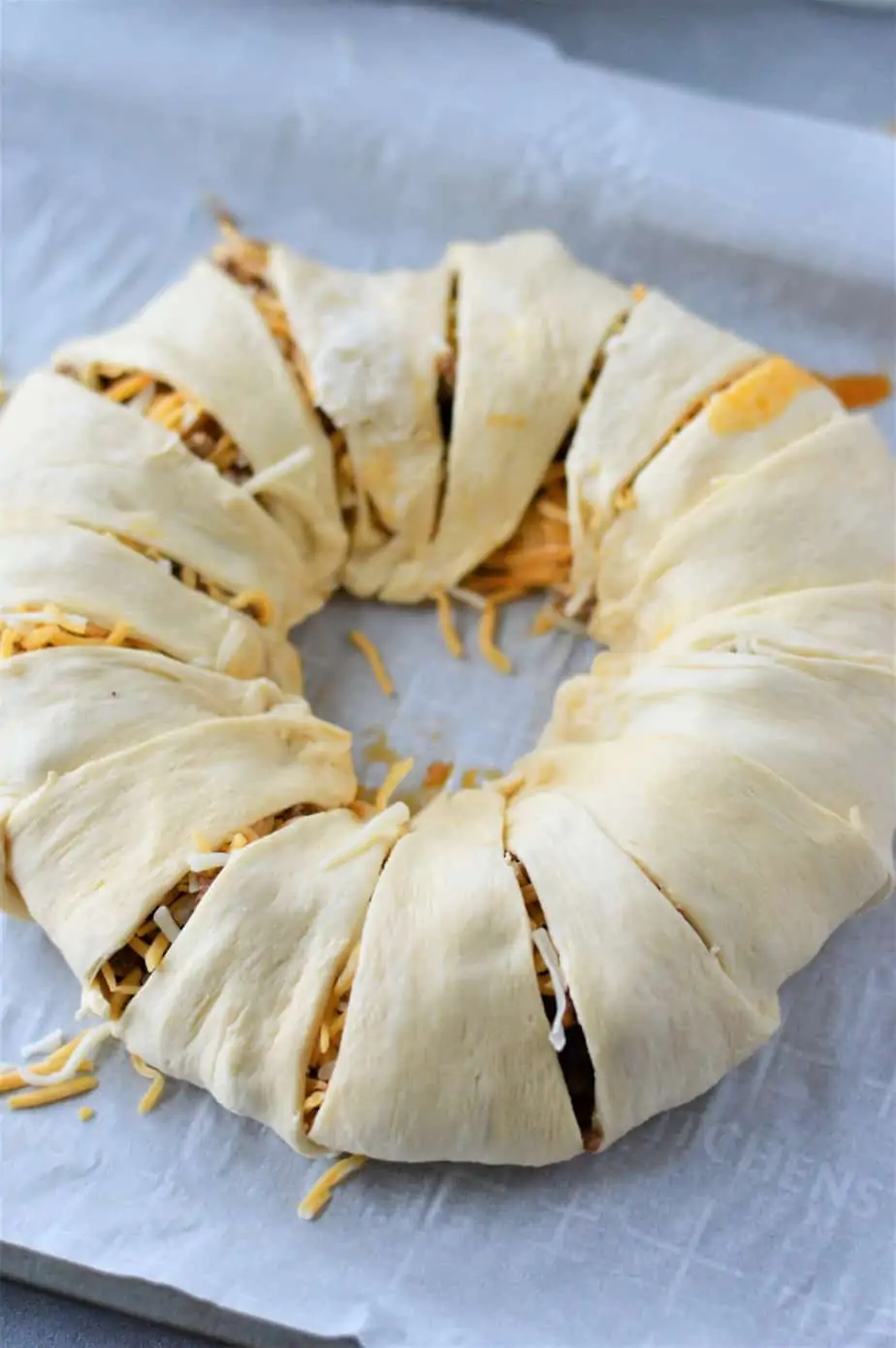 unbaked taco crescent ring on sheet pan lined with parchment paper