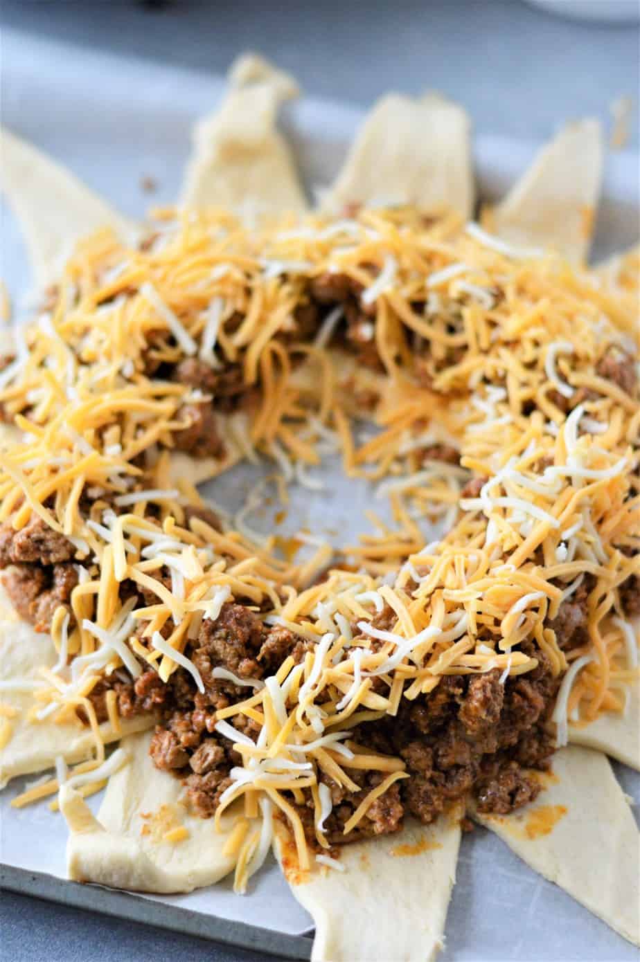 shredded cheese layered on cooked ground beef and crescent roll dough