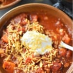 overhead view of turkey and sweet potato chili in bowl garnished with shredded cheese and sour cream