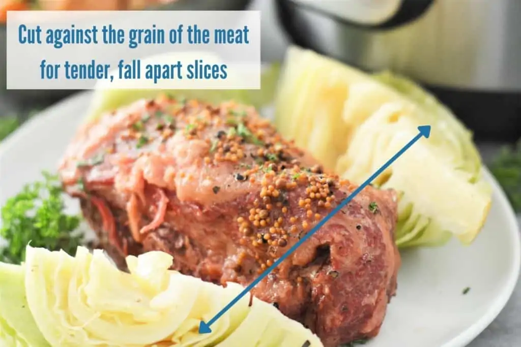 instant pot corned beef brisket on white plate with arrow showing direction to slice meat and text explaining to cut against the grain