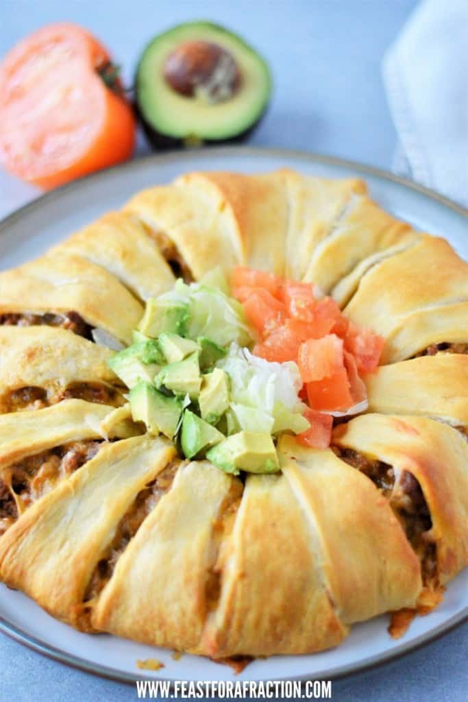 baked crescent roll taco bake on gray platter with avocado and tomato in background