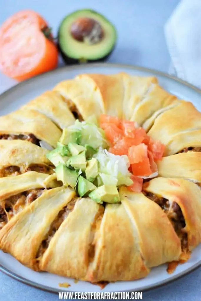 baked crescent roll taco bake on gray platter with avocado and tomato in background