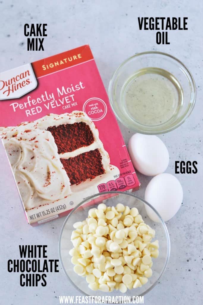 red velvet cake mix, bowl of vegetable oil, two eggs and bowl of white chocolate chips laying on counter