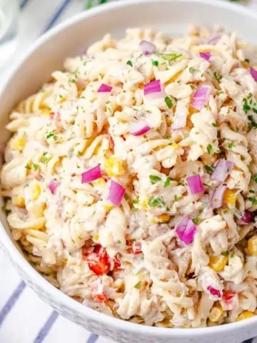 side angle view of tuna pasta salad garnished with chopped red onion