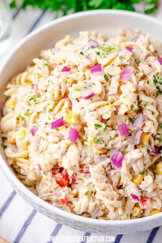 side angle view of tuna pasta salad garnished with chopped red onion
