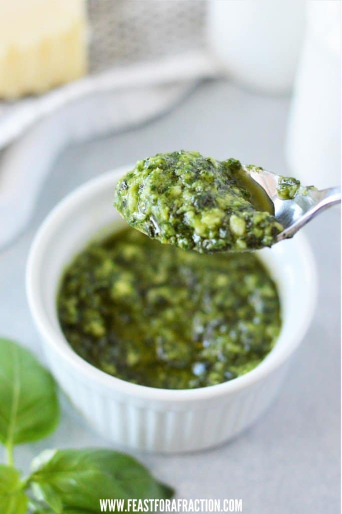 spoon filled with homemade pesto over ramekin of nut free homemade pesto