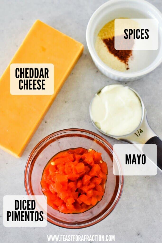 block of cheddar cheese, bowl of diced pimentos, measuring cup of mayonnaise, and bowl of spices to make pimento cheese spread