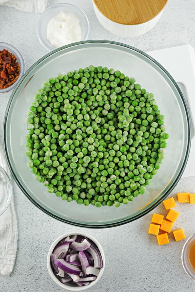 peas in clear glass bowl with other ingredients on side