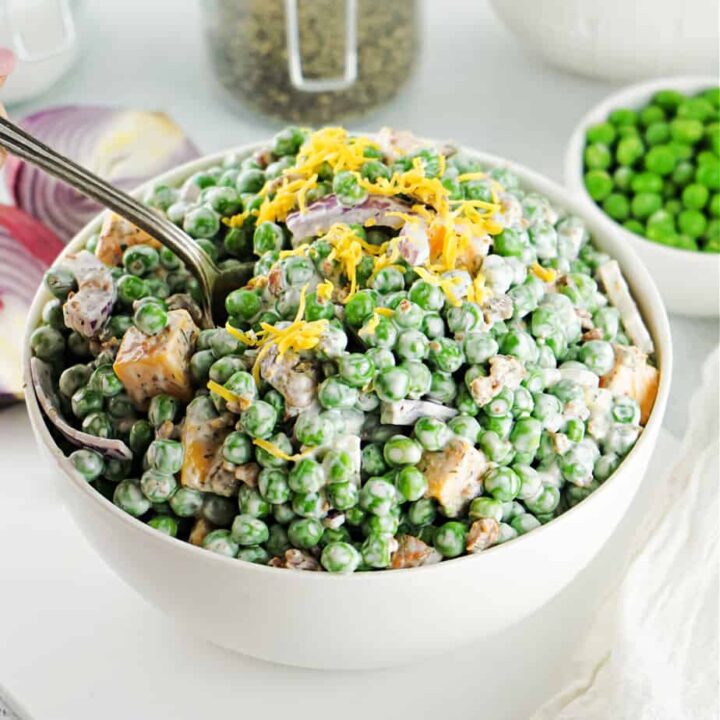 english pea salad in white bowl with spoon