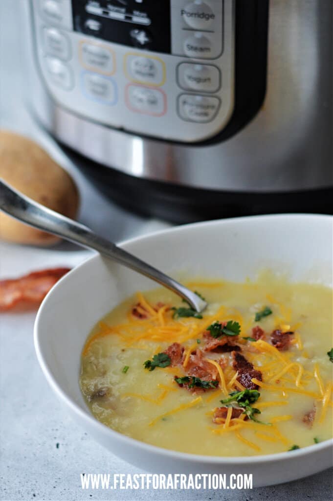potato soup in white bowl with spoon and cheese, bacon and parsley