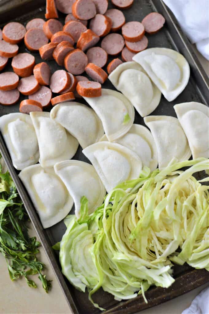 cabbage, pierogi and sausage on baking sheet