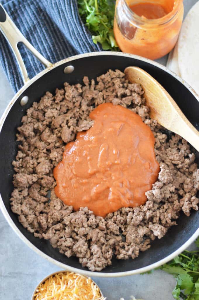 enchilada sauce with cooked ground beef in skillet