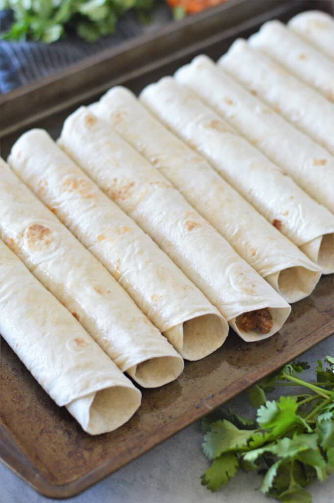 taquitos rolled on baking sheet ready for oven
