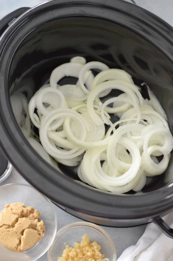 A slow cooker filled with onions and other ingredients creates a flavorful pork loin recipe.