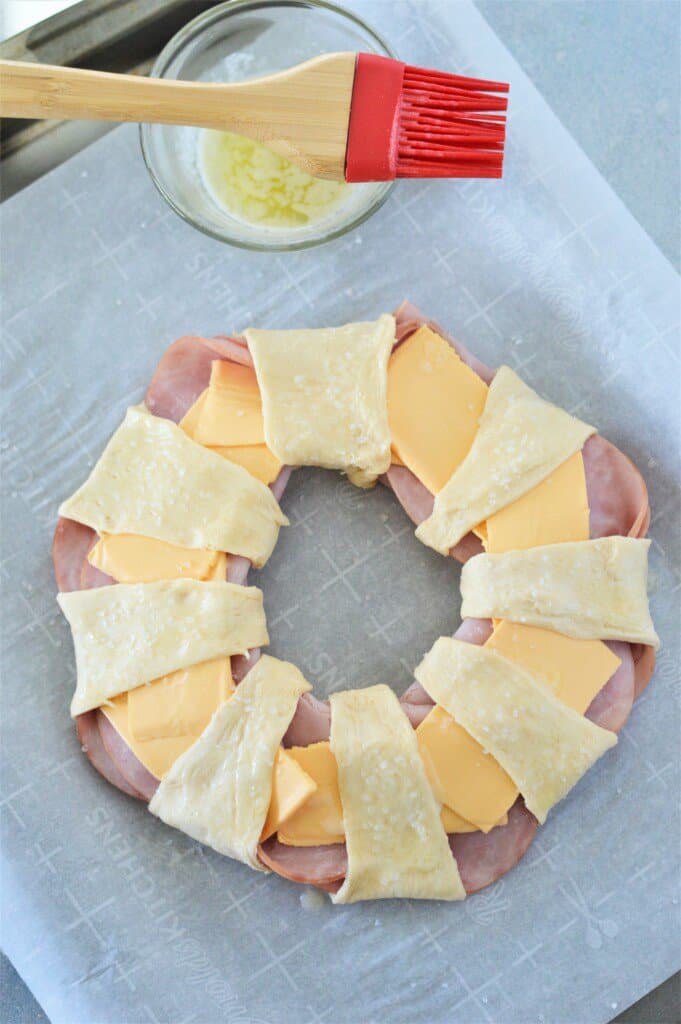 unbaked ham and cheese ring on sheet pan lined with parchment paper