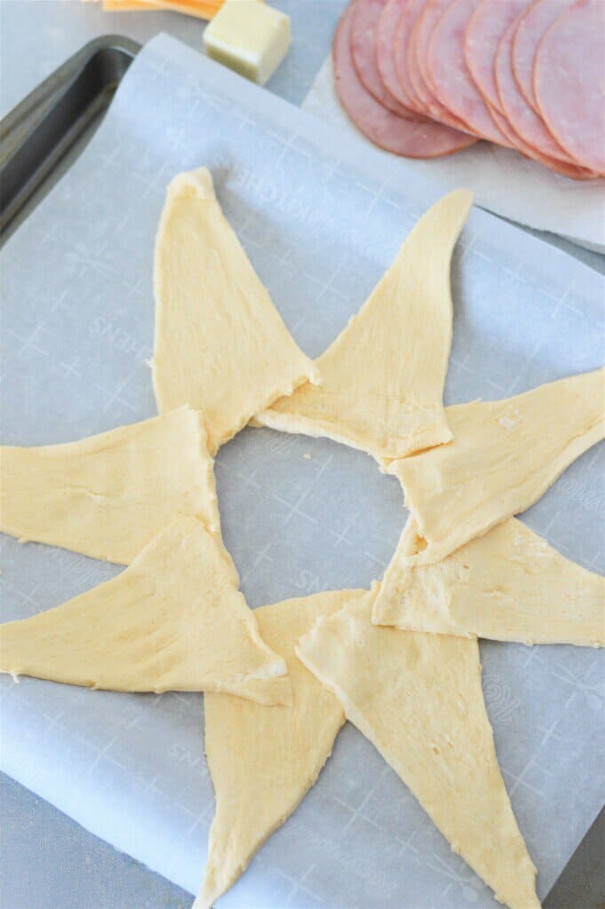 crescent roll dough triangles shaped in a ring with pointy end outward on parchment lined baking pan