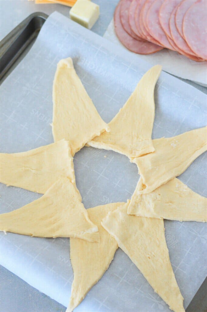 crescent roll dough triangles shaped in a ring with pointy end outward on parchment lined baking pan