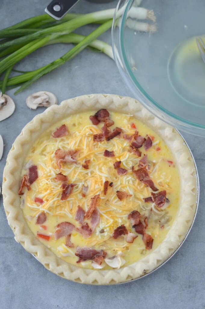 overhead view of quiche egg mixture in pie crust topped with bacon