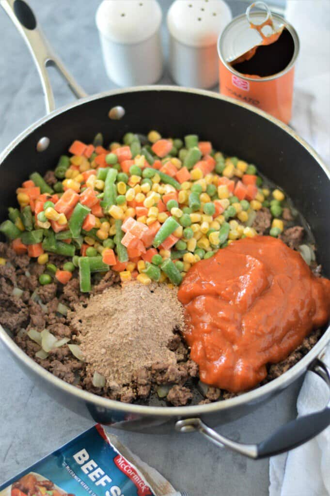 frozen mixed vegetables, beef stew seasoning and canned tomato soup in pan with ground beef