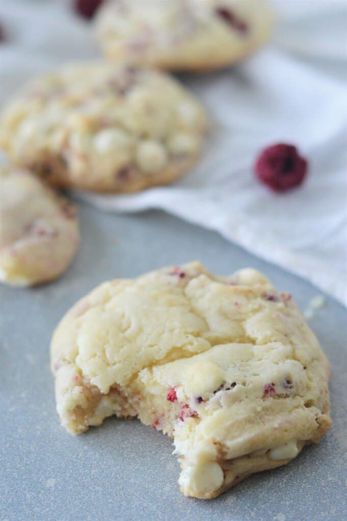 white chocolate raspberry cake mix cookie on blue countertop with white tea towel in background