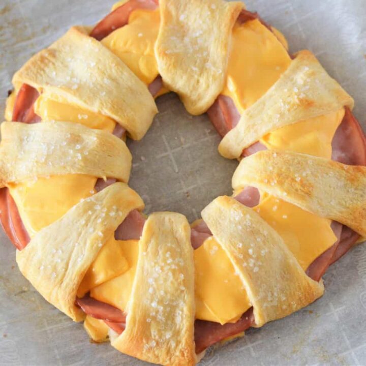 square image of overhead view of baked ham and cheese crescent ring on parchment paper