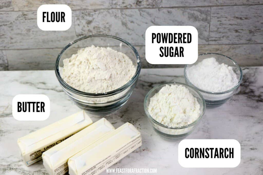 ingredients for whipped shortbread cookies: flour, butter, powdered sugar, and cornstarch on counter