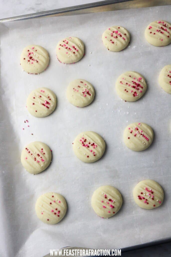 overhead view of baked whipped shortbread cookies on baking pan with parchment paper