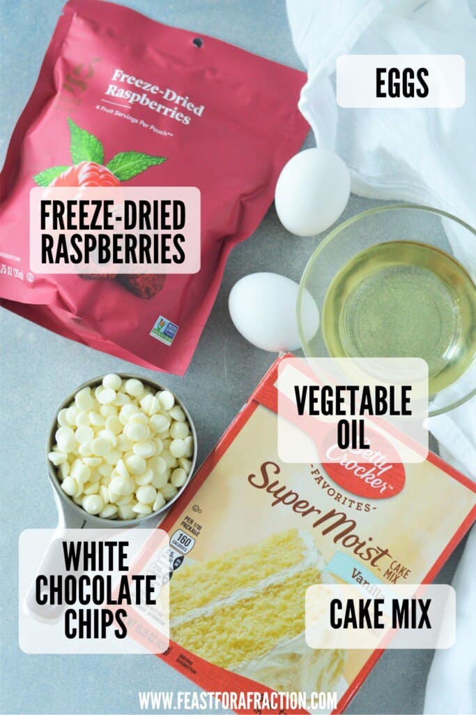 ingredients for cake mix cookies: eggs, vegetable oil, cake mix, white chocolate chips, and freeze-dried raspberries