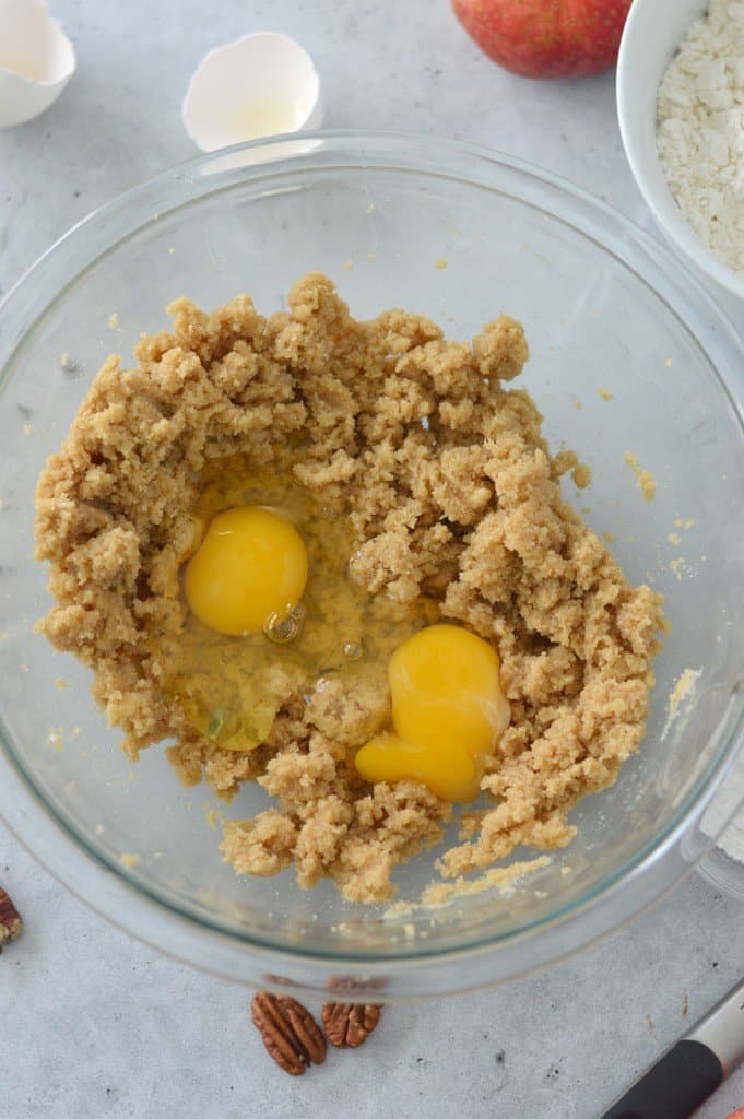 Eggs and brown sugar in a glass bowl.