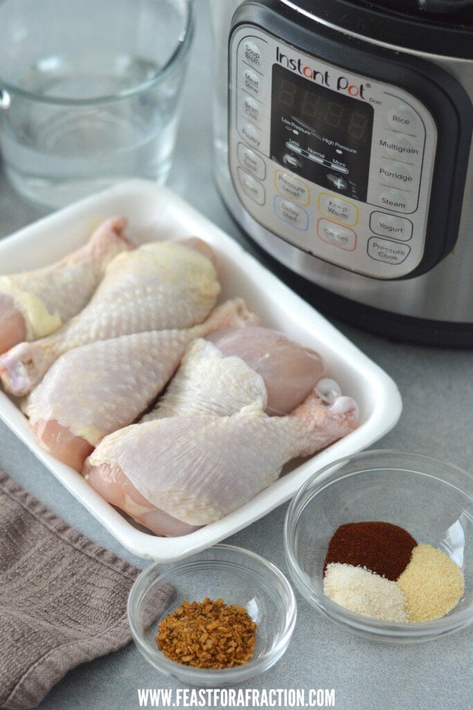 Chicken legs and an instant pot with spices and seasonings.