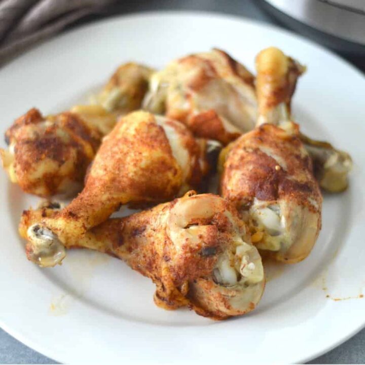 Chicken legs on a plate in front of an instant pot.