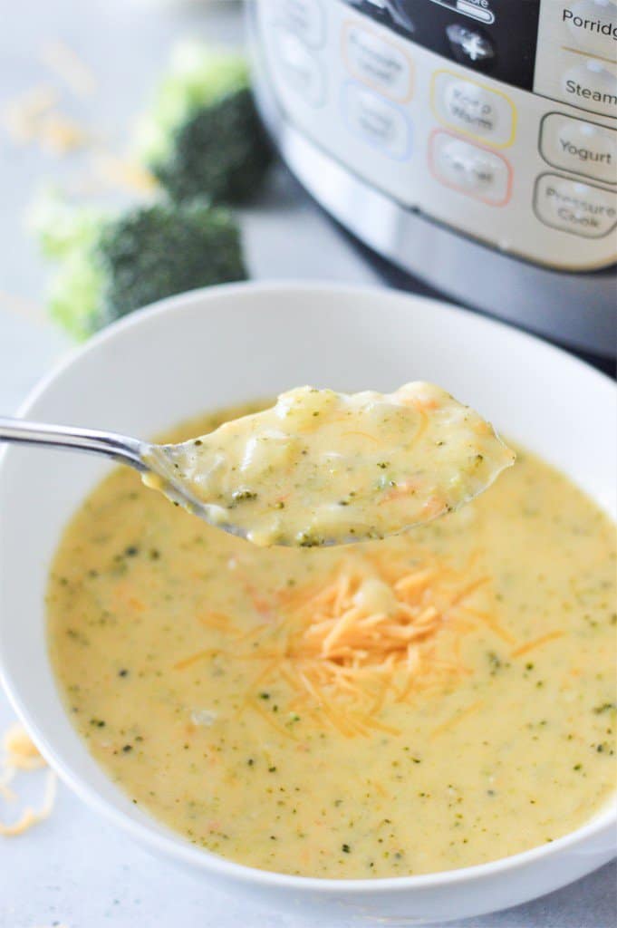 Instant pot broccoli cheese soup in a white bowl with spoon and instant pot in background