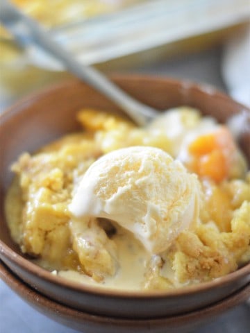 Peach cobbler dump cake with ice cream in a bowl.