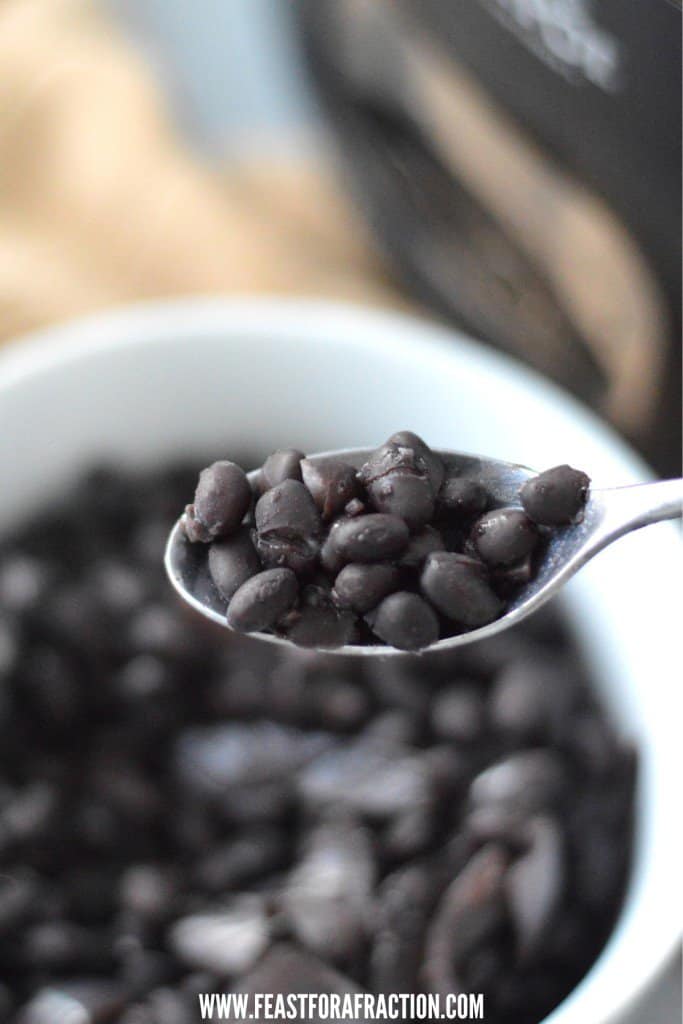 A spoonful of black beans in a bowl.