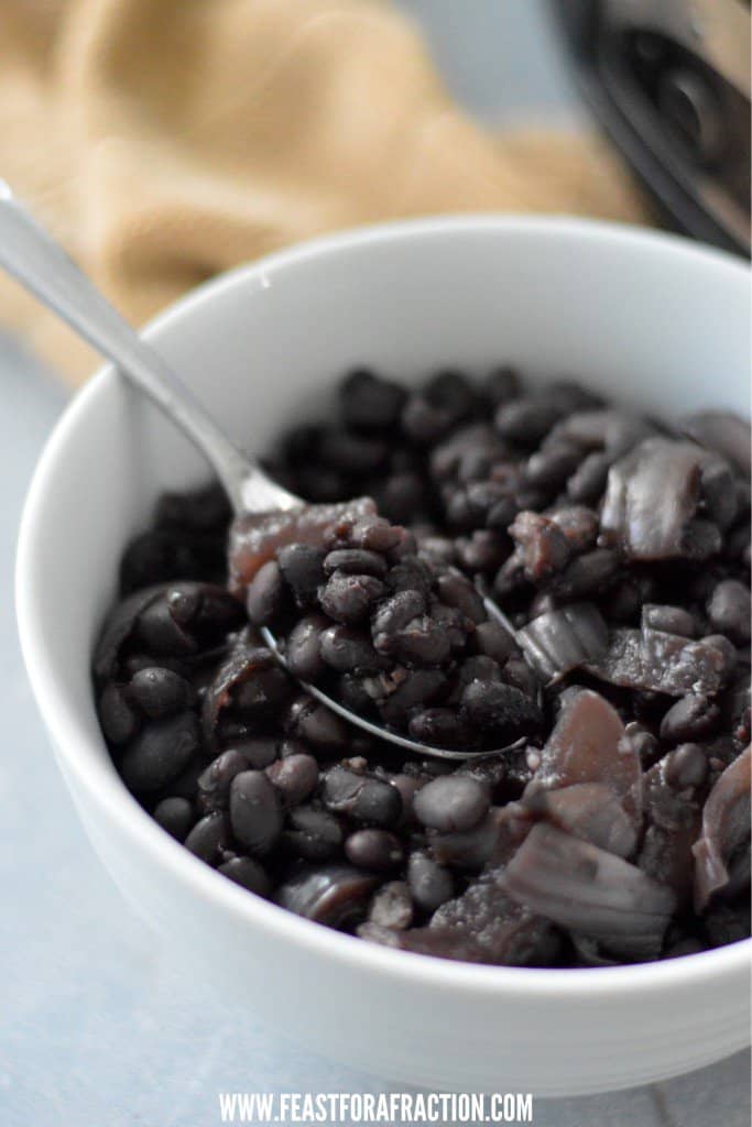 Black beans in a bowl with a spoon.