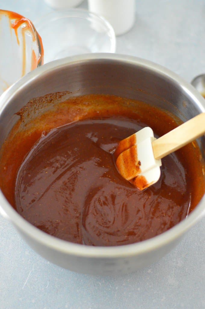 A bowl of homemade bbq sauce with a wooden spoon in it.