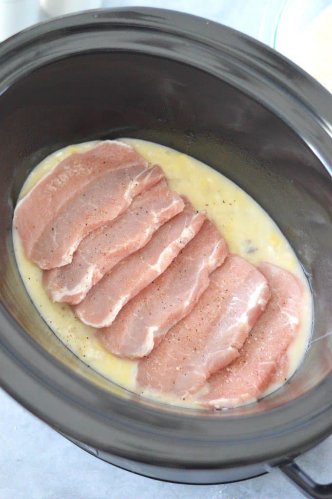 Pork chops in a slow cooker with rice and soup.
