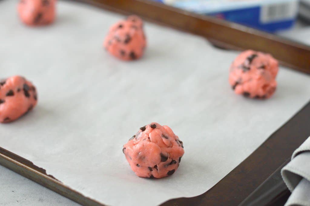 strawberry chocolate chip cookie dough balls on a baking sheet.
