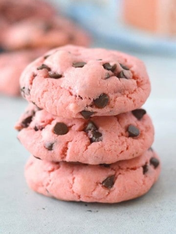 Pink chocolate chip cookies stacked on top of each other.
