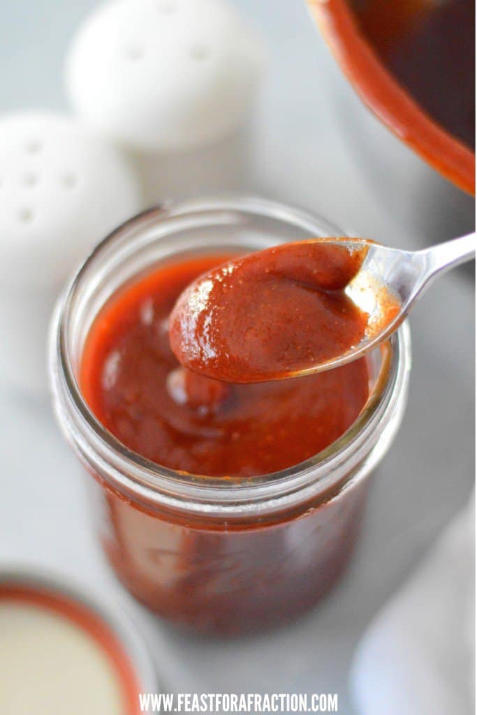 homemade no-cook bbq sauce in a mason jar with spoon. salt and pepper shakers in background