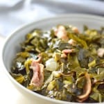 side view of collard greens with bacon in bowl with instant pot in background