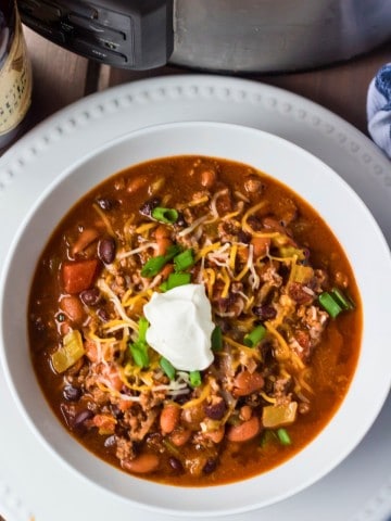 A bowl of guinness chili in front of a slow cooker.