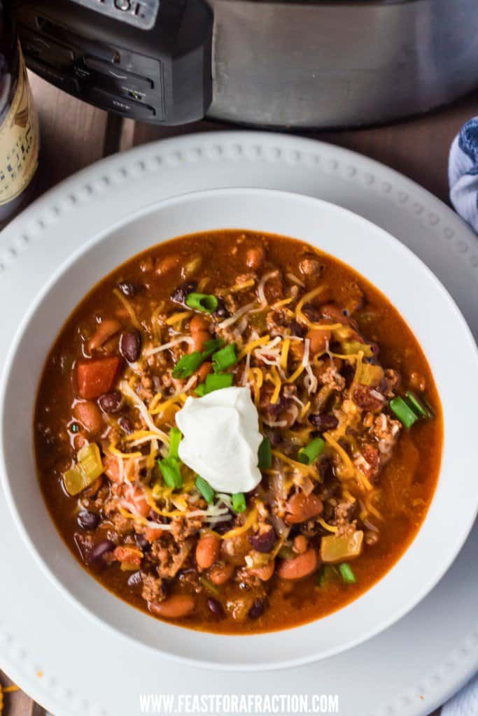 A bowl of guinness chili in front of a slow cooker.