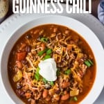Slow cooker guinness chili in a white bowl garnished with green onions and sour cream with title text