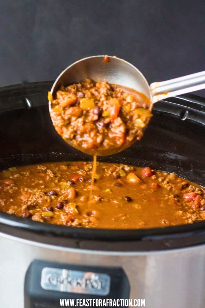 A spoonful of chili in a crock pot.