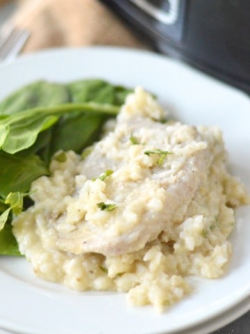 boneless pork chop and creamy rice on stacked white plates with slow cooker in background